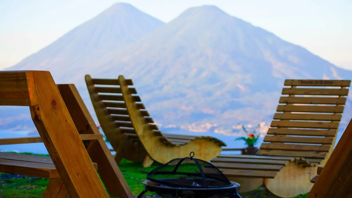 Sillas de madera y fogata frente a los volcanes del lago de Atitlán
