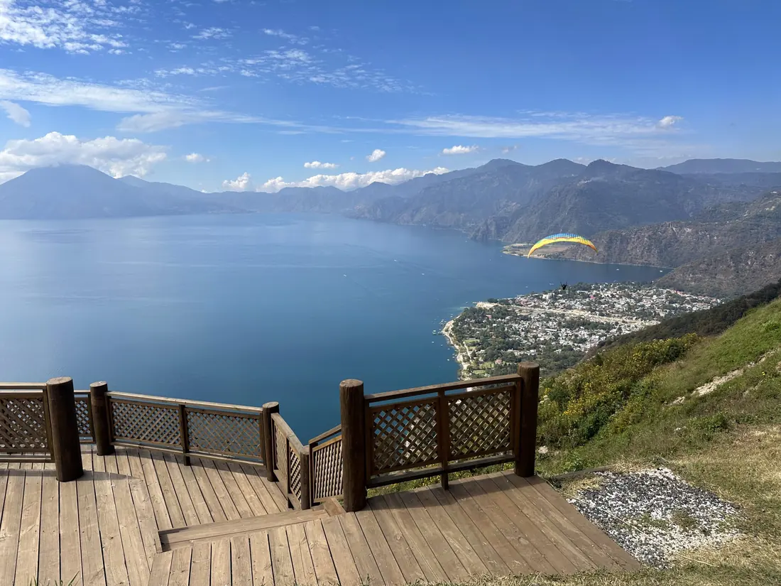 Vista del lago de Atitlán desde el aire, con un parapente sobrevolando la costa de Panajachel